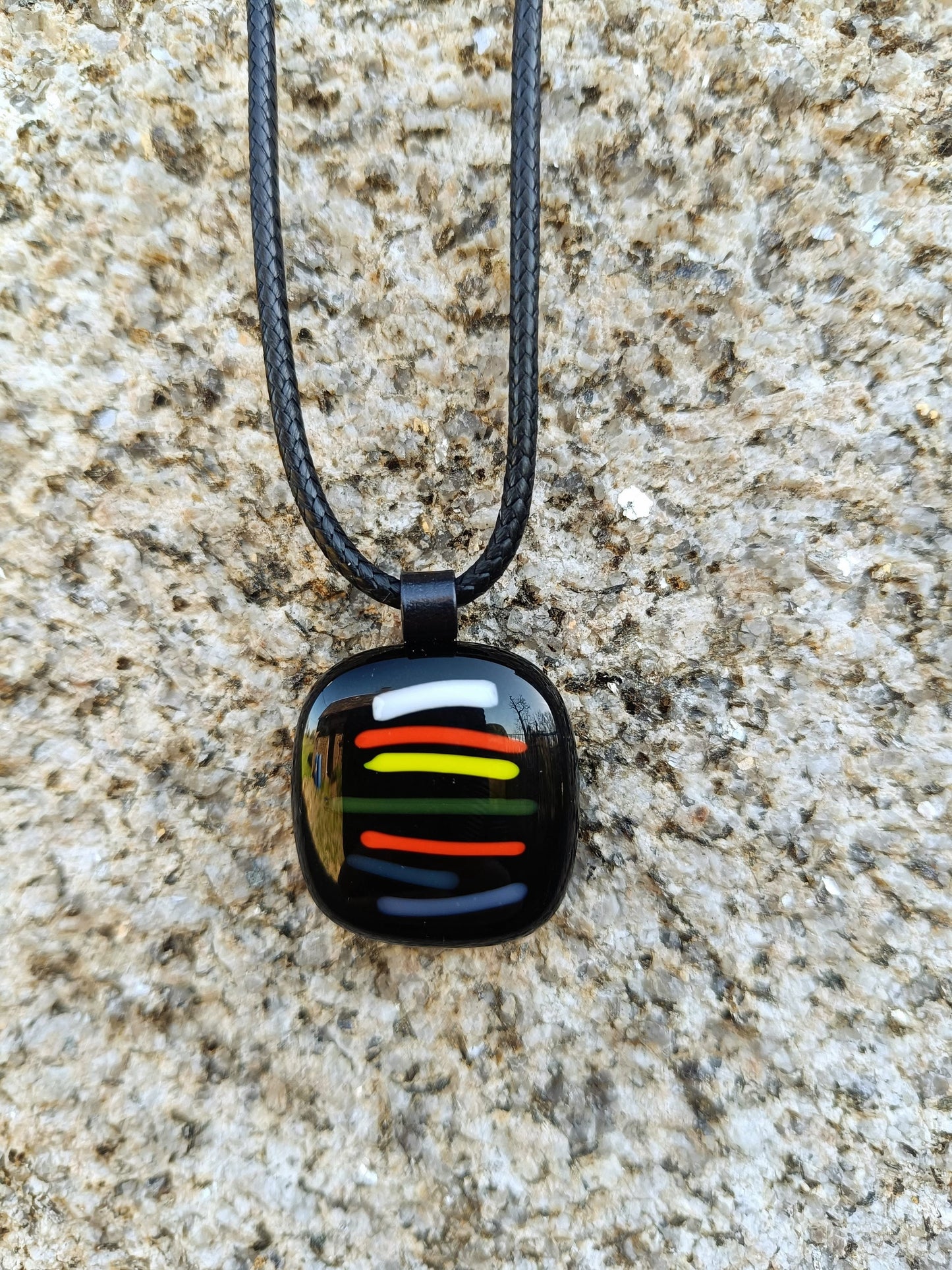 colourful fused glass pendant hanging against a wall
