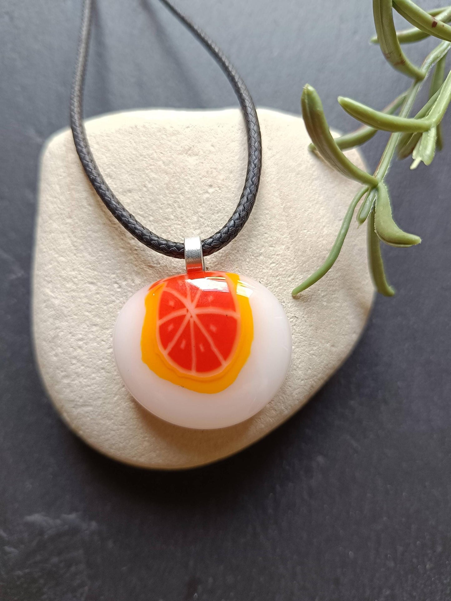 Fused glass orange pendant necklace on black cord; white round disc with bright orange slice, handmade one-of-a-kind jewelry.