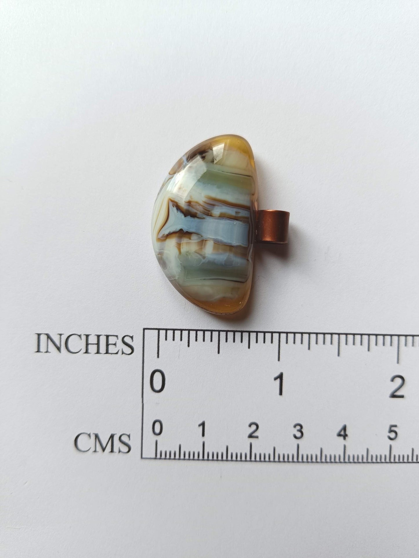 Fused glass pendant on a grunge black cord necklace with copper bail; orange bottom with blue-green swirls and brown lines.