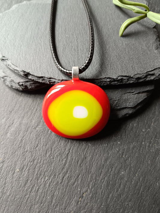 Round fused glass pendant in red, yellow and lime green on a black chain; handmade jewelry, statement pendant.