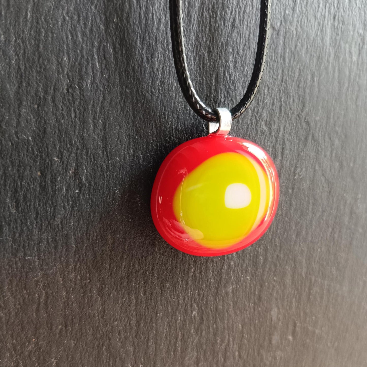 Round fused glass pendant in red, yellow and lime green on a black chain; handmade jewelry, statement pendant.