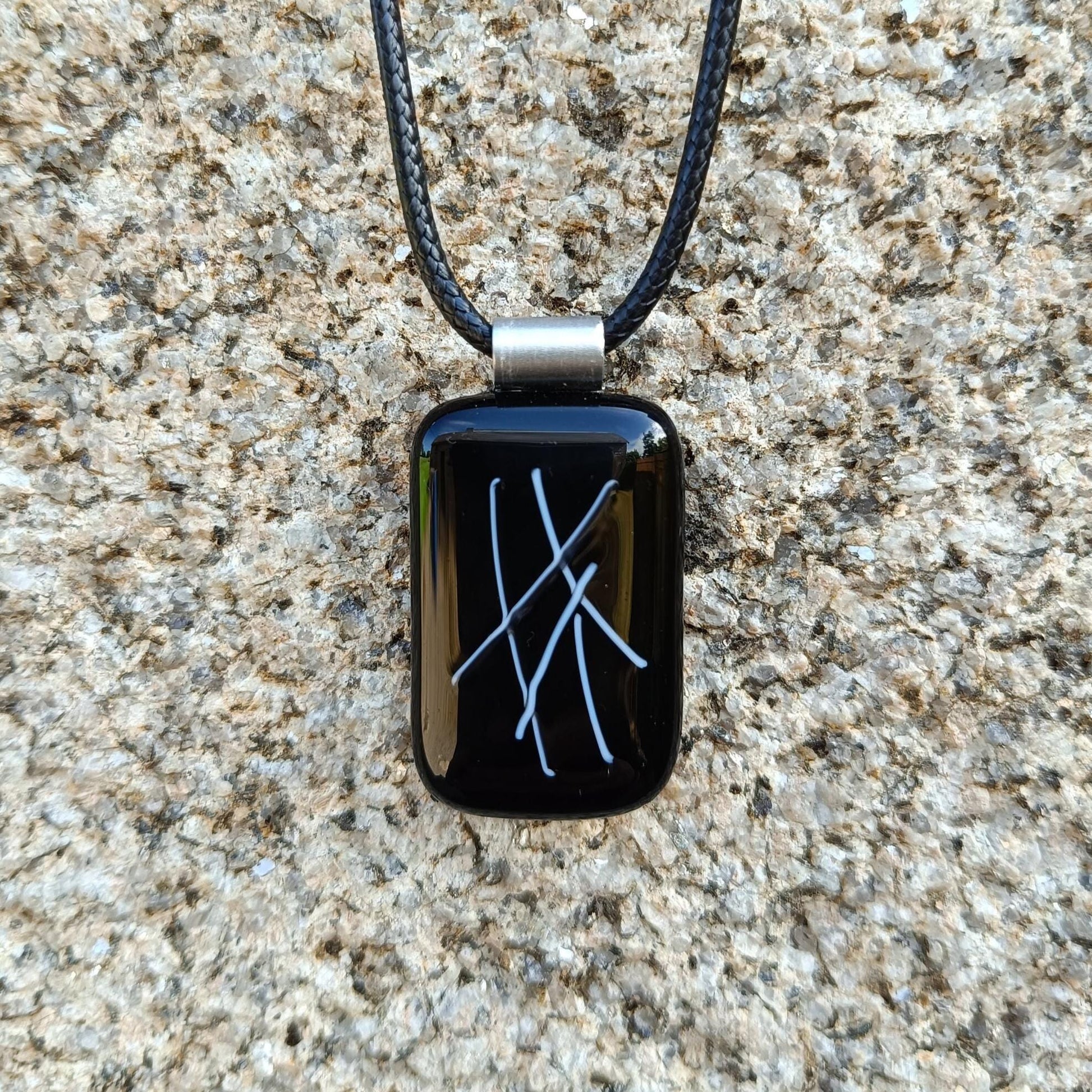 hand crafted black glass pendant hanging on a cord