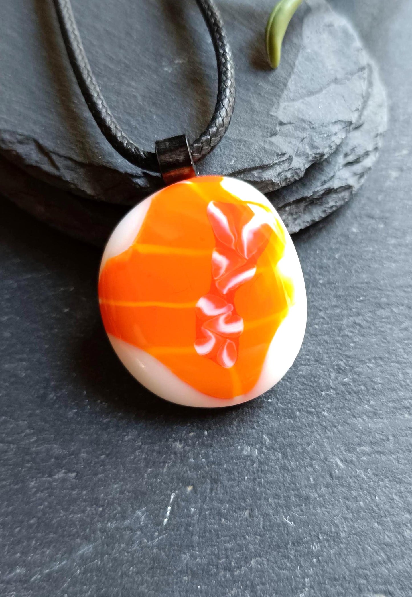 Orange fused glass pendant on black cord necklace; round cabochon with orange and white swirls, boho handmade jewellery.