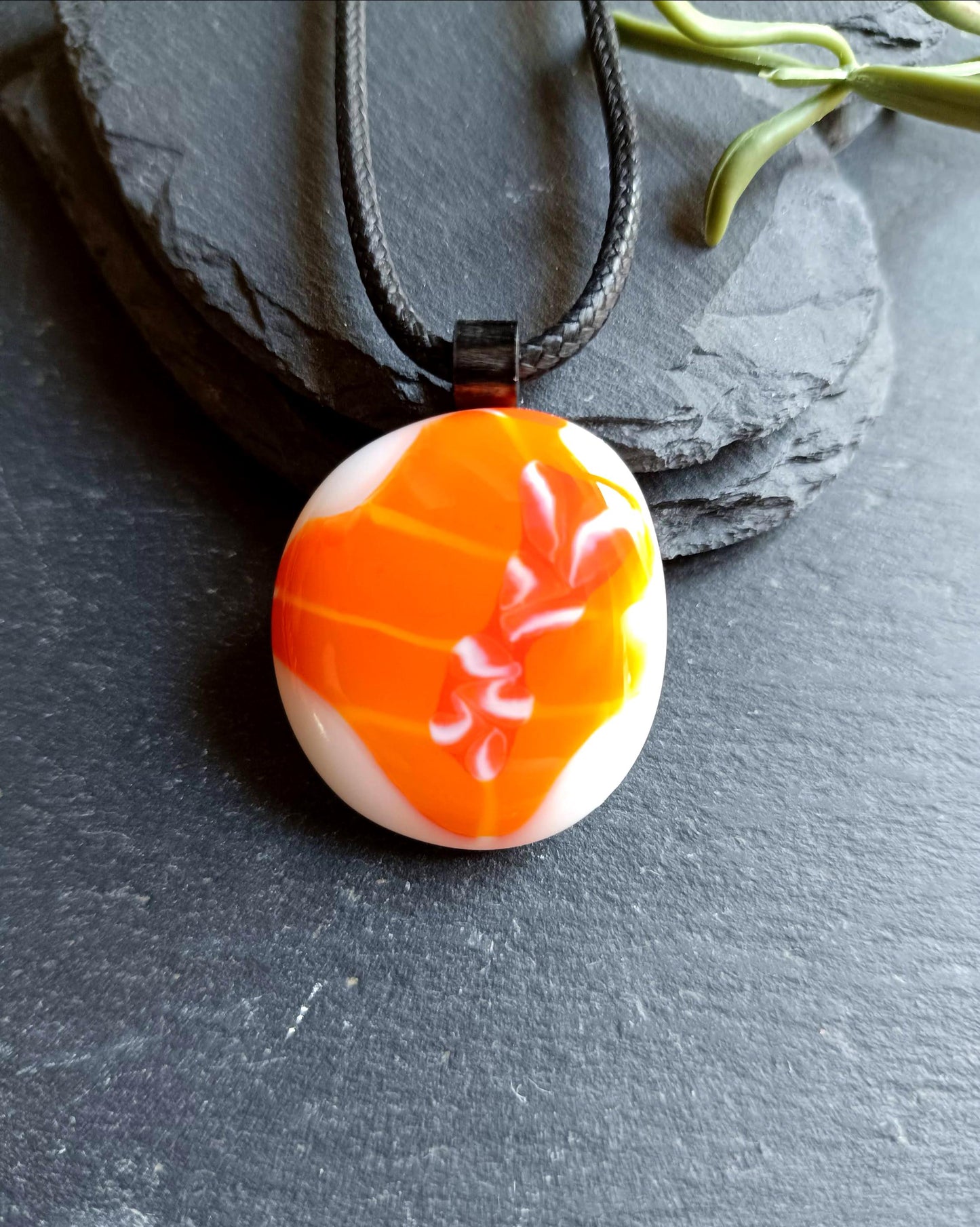 Orange fused glass pendant on black cord necklace; round cabochon with orange and white swirls, boho handmade jewellery.