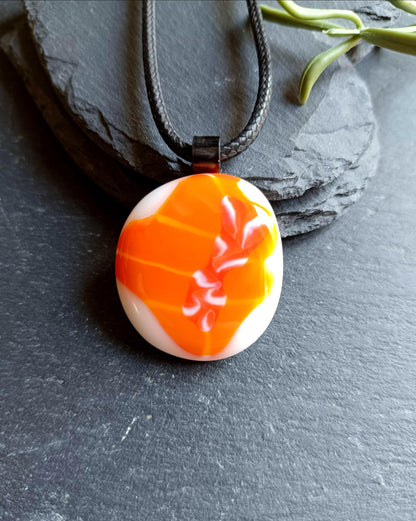 Orange fused glass pendant on black cord necklace; round cabochon with orange and white swirls, boho handmade jewellery.