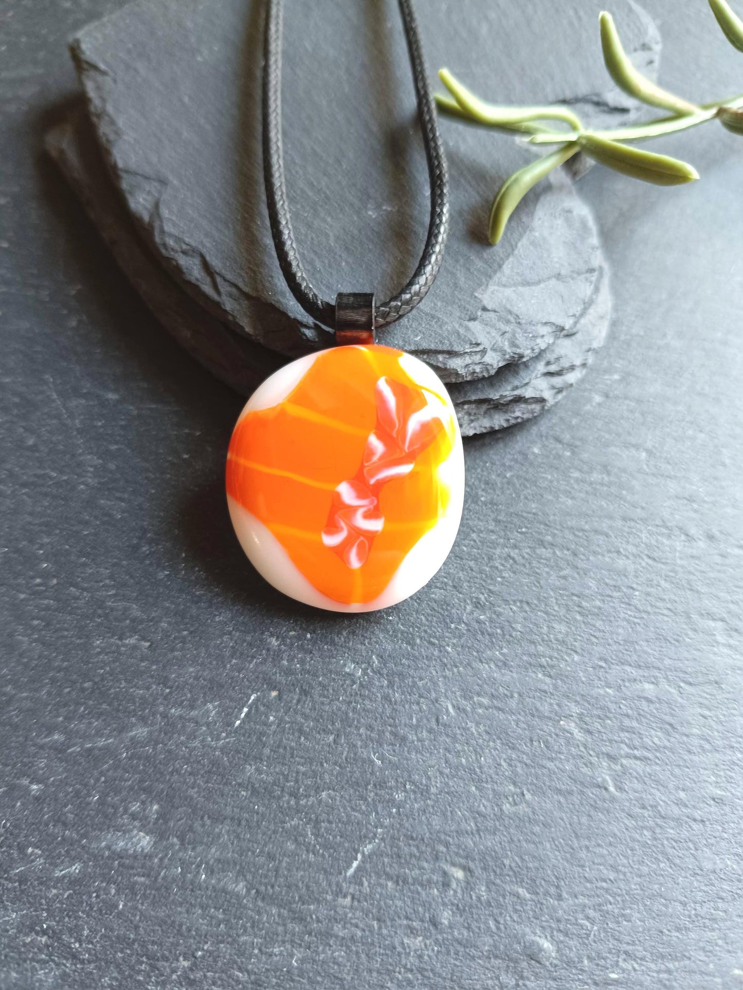 Orange fused glass pendant on black cord necklace; round cabochon with orange and white swirls, boho handmade jewellery.