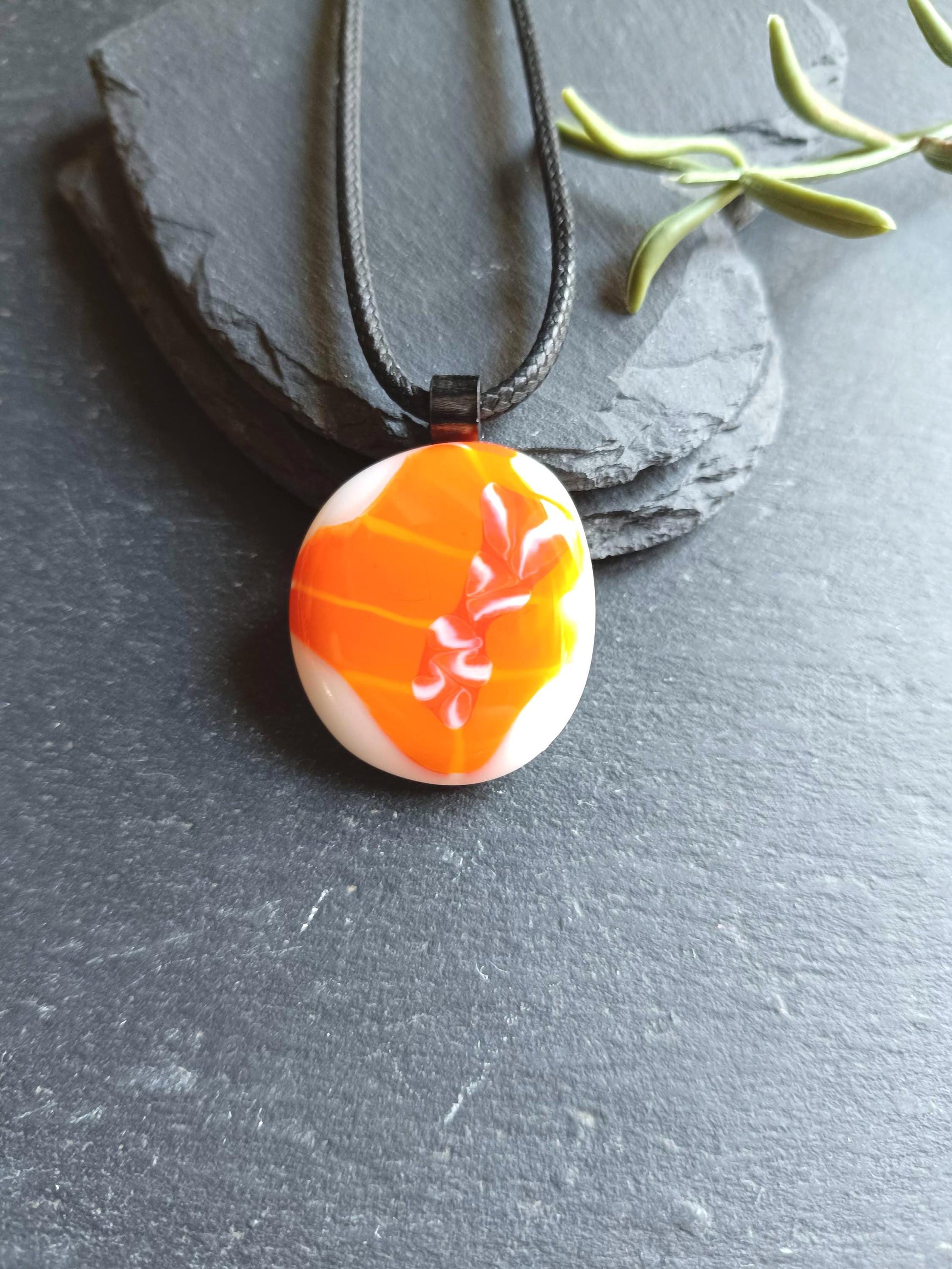 Orange fused glass pendant on black cord necklace; round cabochon with orange and white swirls, boho handmade jewellery.
