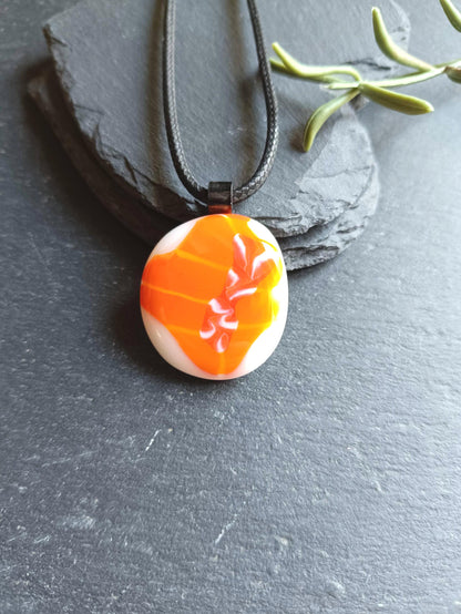 Orange fused glass pendant on black cord necklace; round cabochon with orange and white swirls, boho handmade jewellery.