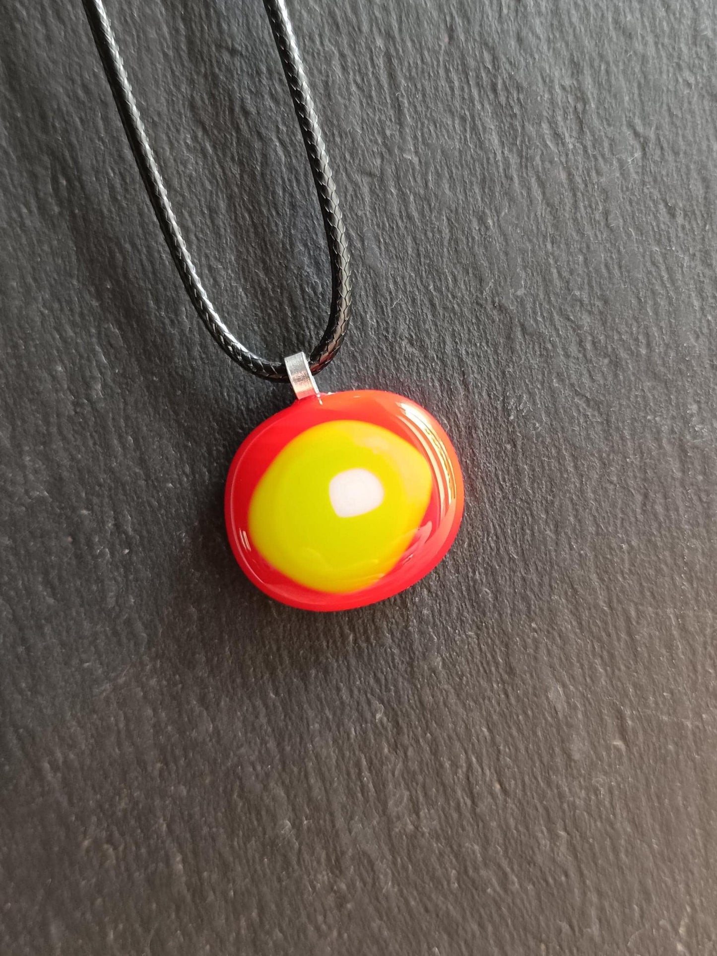 Round fused glass pendant in red, yellow and lime green on a black chain; handmade jewelry, statement pendant.