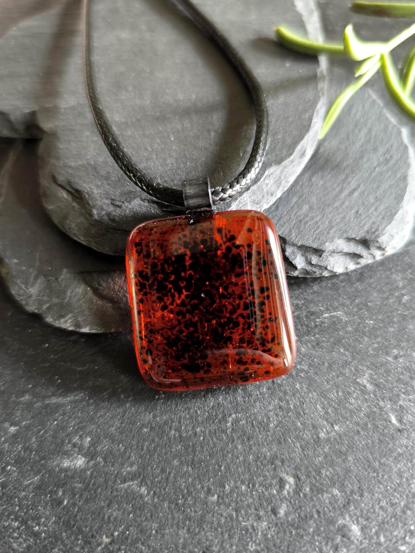 Red transparent fused glass pendant on a dark cord necklace; handmade necklace with black speckles.