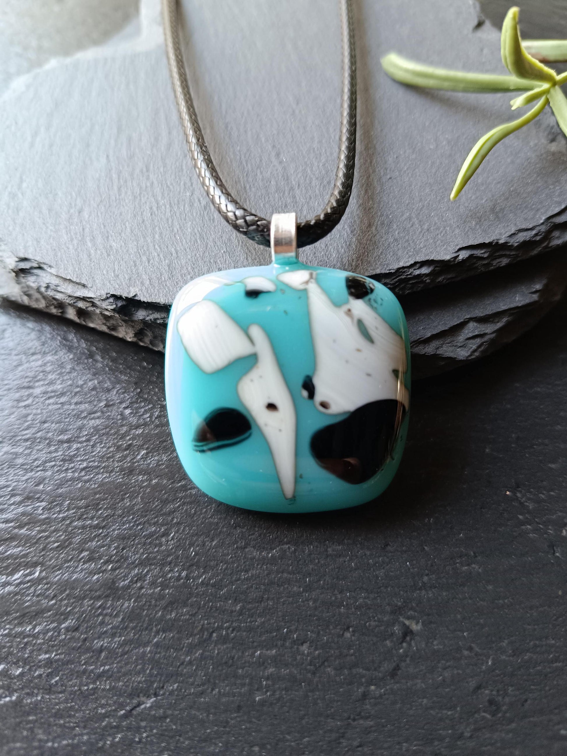 Fused glass pendant on black cord; turquoise blue square with white and black abstract patterns, handmade, easy to mail.