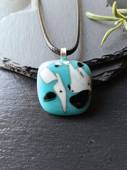 Fused glass pendant on black cord; turquoise blue square with white and black abstract patterns, handmade, easy to mail.