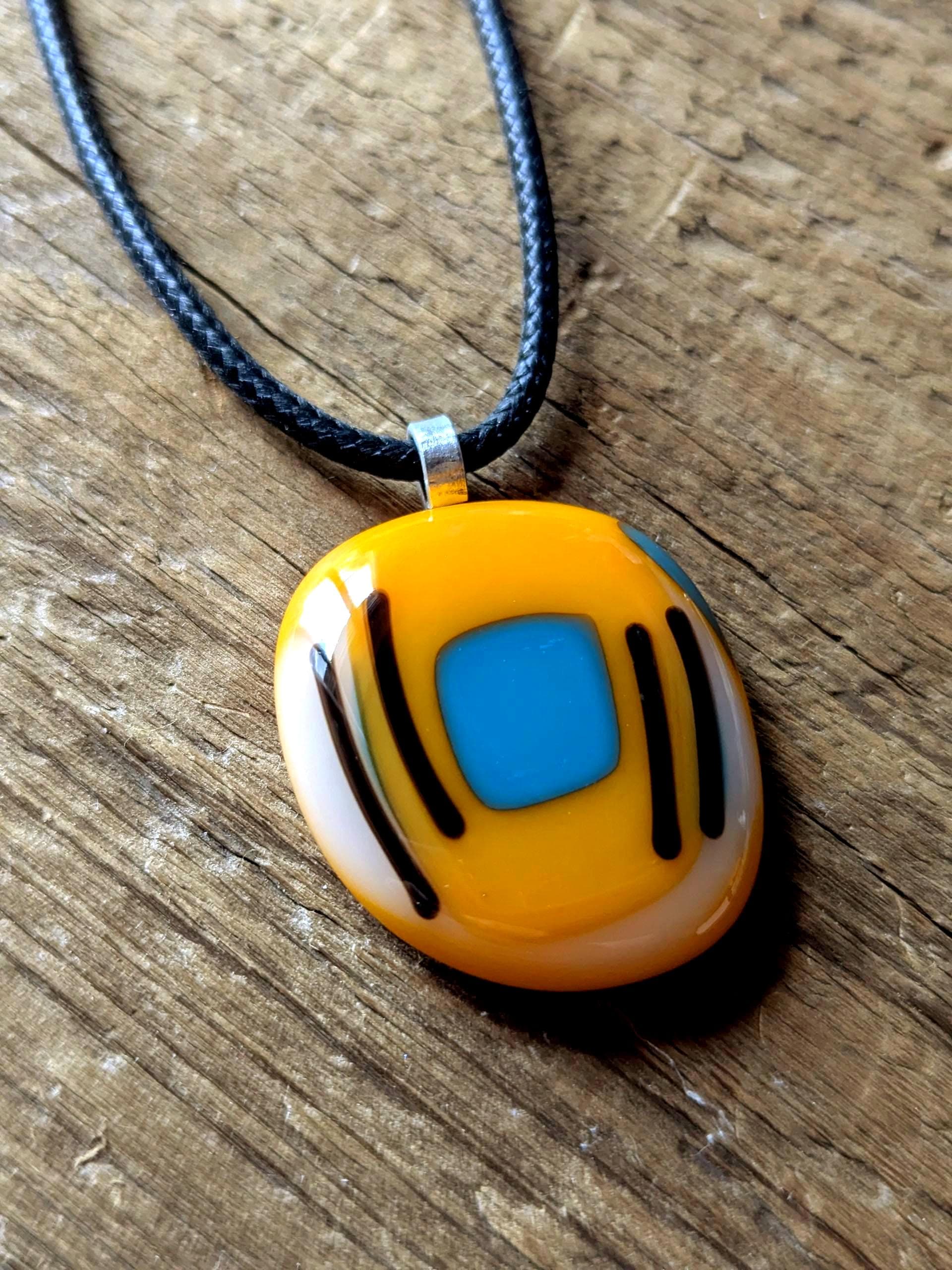 Orange fused glass pendant with blue square and black lines on a black cord necklace - boho statement handmade jewellery.