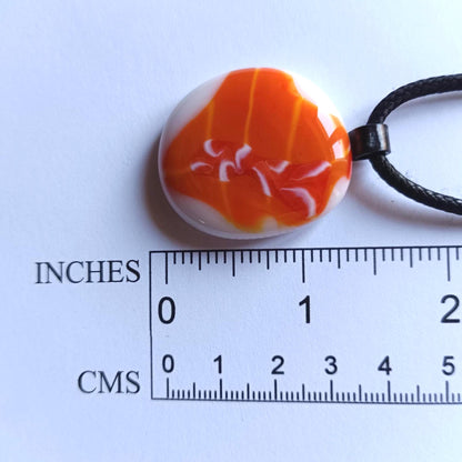 Orange fused glass pendant on black cord necklace; round cabochon with orange and white swirls, boho handmade jewellery.