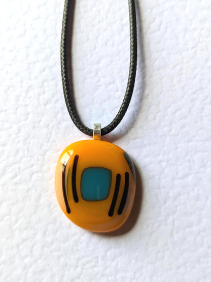 Orange fused glass pendant with blue square and black lines on a black cord necklace - boho statement handmade jewellery.