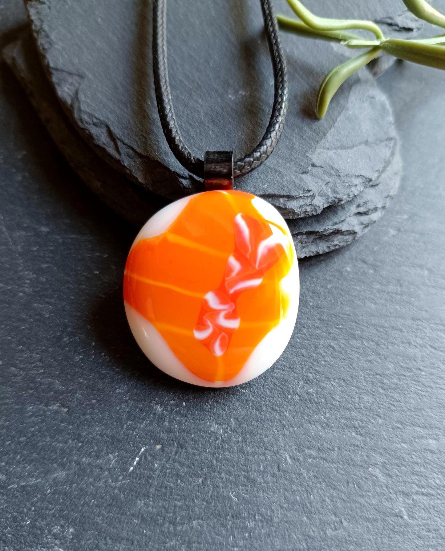 Orange fused glass pendant on black cord necklace; round cabochon with orange and white swirls, boho handmade jewellery.