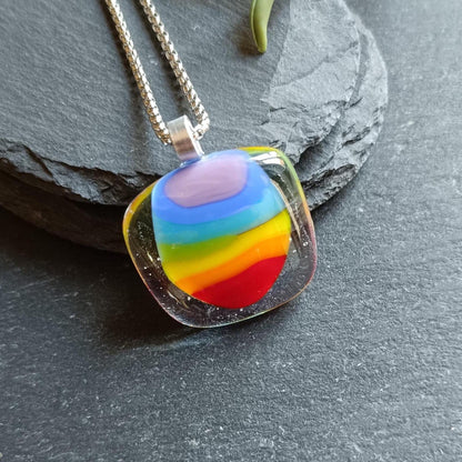 Handmade fused glass rainbow pendant necklace on a silver chain; colorful stripes in a clear rounded-square pendant.