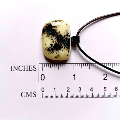 One-of-a-kind fused glass pendant on dark cord; cream vanilla with black splatters and teal specks, handmade boho Gothic.