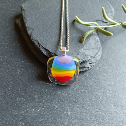 Handmade fused glass rainbow pendant necklace on a silver chain; colorful stripes in a clear rounded-square pendant.