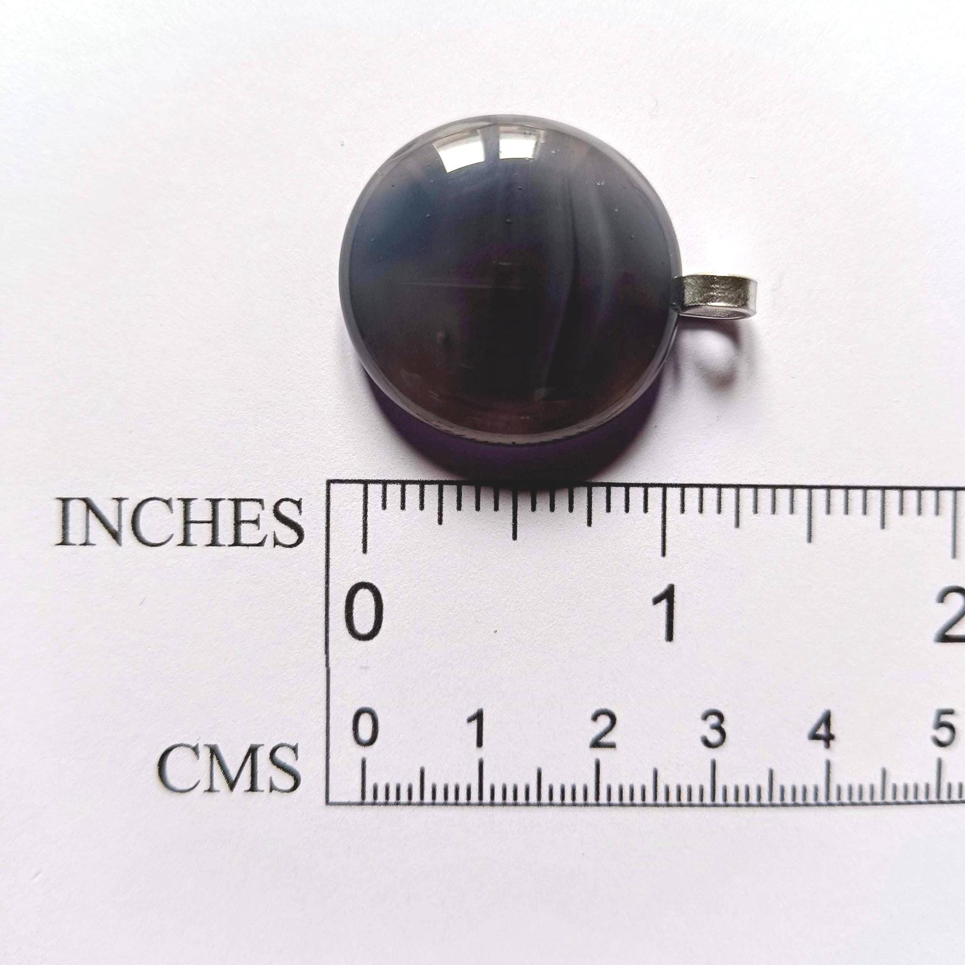 grey pendant next to a ruler