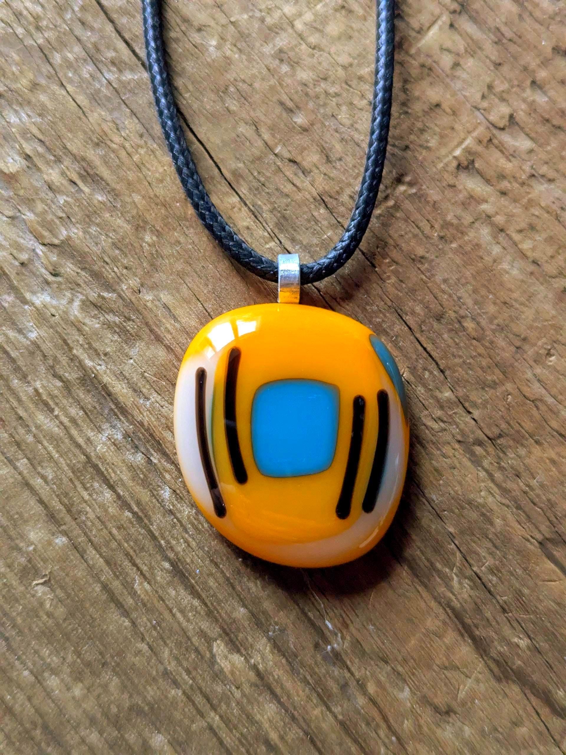 Orange fused glass pendant with blue square and black lines on a black cord necklace - boho statement handmade jewellery.