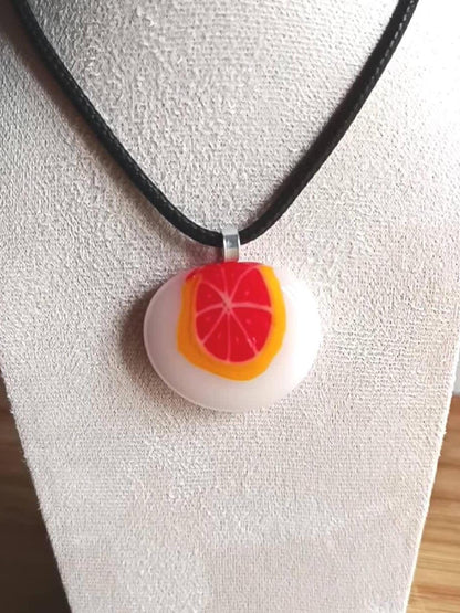 Fused glass orange pendant necklace on black cord; white round disc with bright orange slice, handmade one-of-a-kind jewelry.