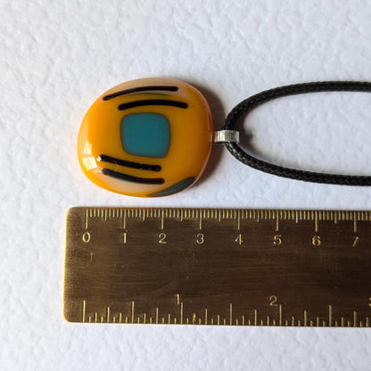 Orange fused glass pendant with blue square and black lines on a black cord necklace - boho statement handmade jewellery.