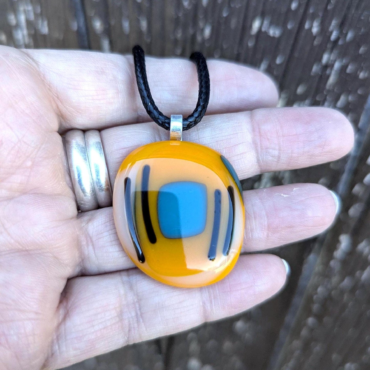 Orange fused glass pendant with blue square and black lines on a black cord necklace - boho statement handmade jewellery.