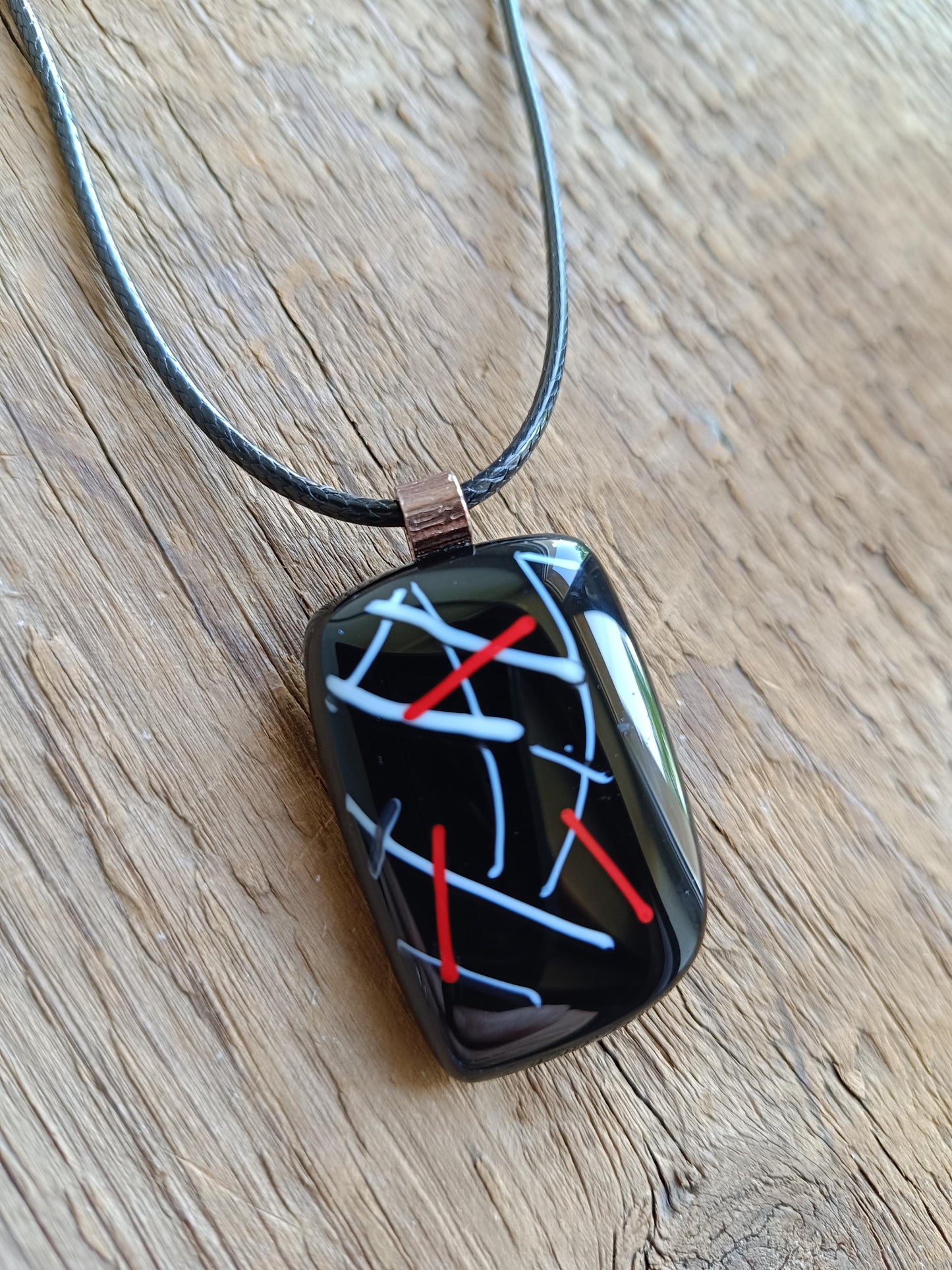 Fused glass pendant on black cord necklace with abstract white, blue, red lines; quirky art pendant, handmade jewellery.