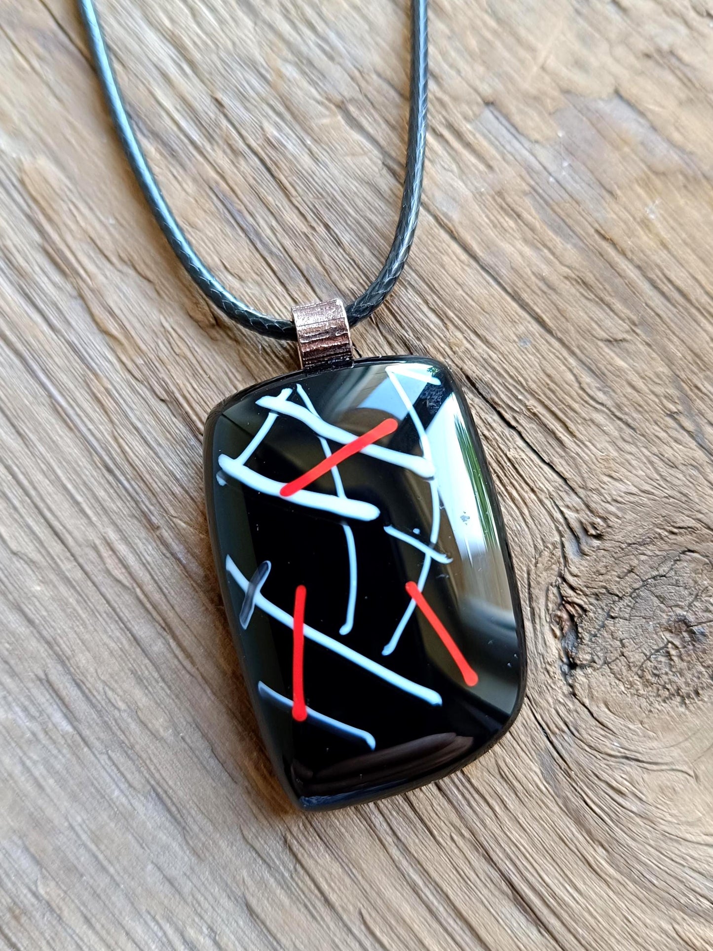 Fused glass pendant on black cord necklace with abstract white, blue, red lines; quirky art pendant, handmade jewellery.