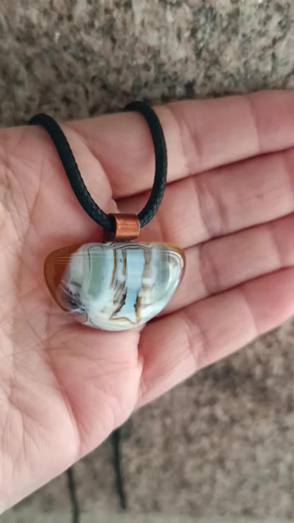 Fused glass pendant on a grunge black cord necklace with copper bail; orange bottom with blue-green swirls and brown lines.
