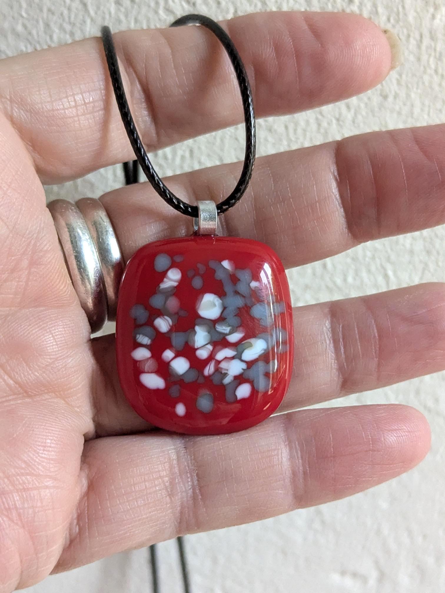 Red fused glass speckled pendant on brown cord necklace; one-of-a-kind handmade jewellery.