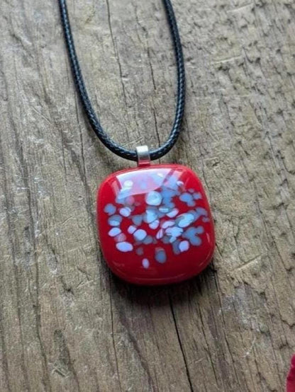 Red fused glass speckled pendant on brown cord necklace; one-of-a-kind handmade jewellery.