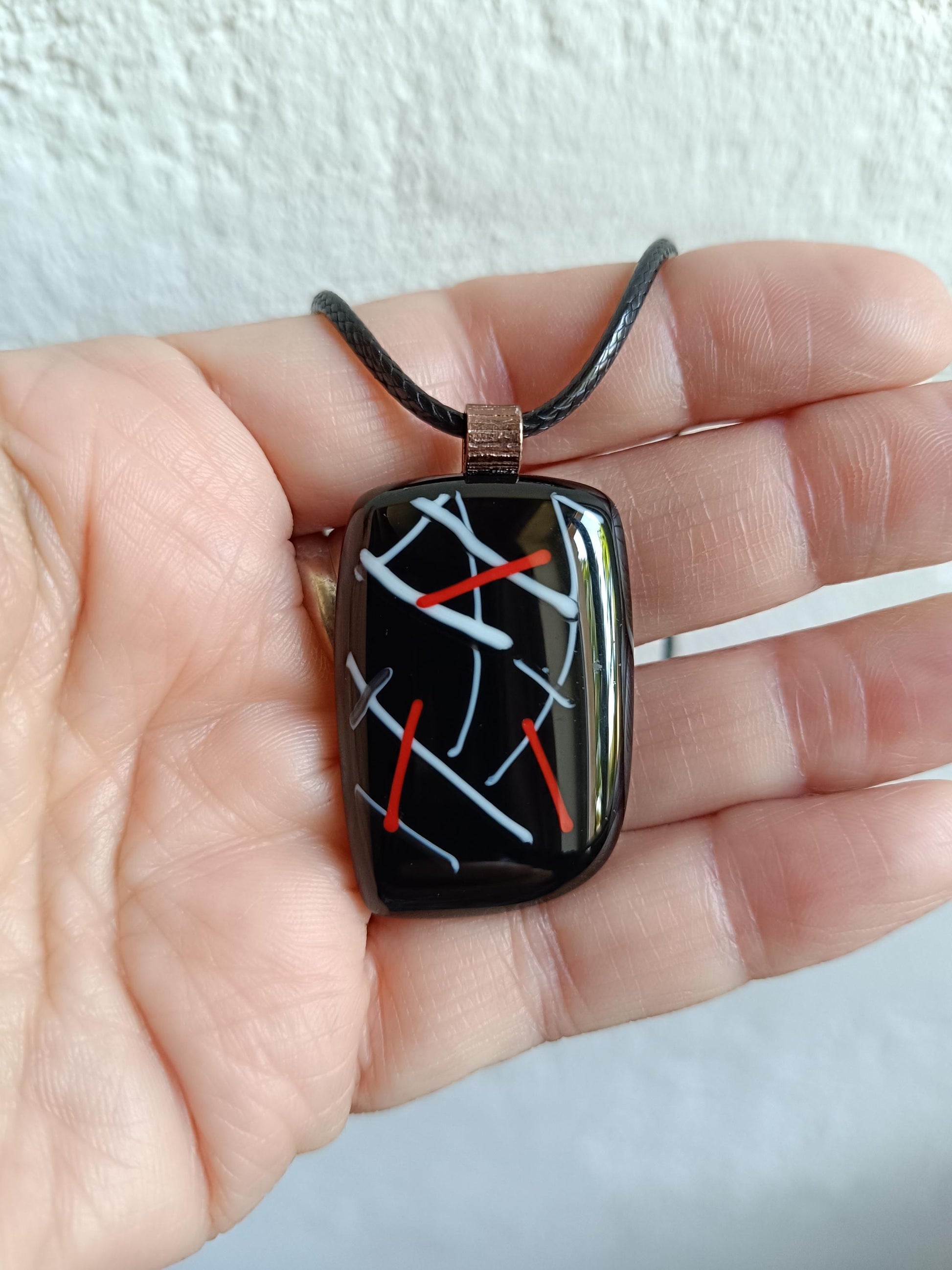 Fused glass pendant on black cord necklace with abstract white, blue, red lines; quirky art pendant, handmade jewellery.