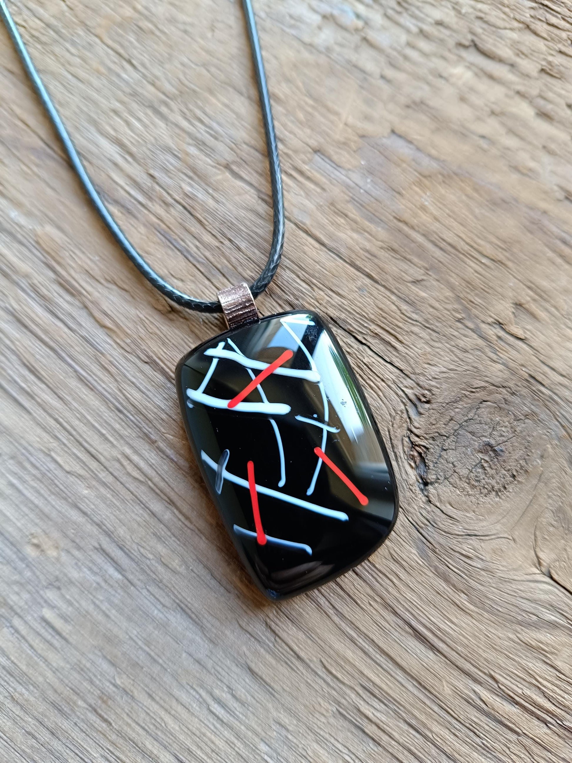 Fused glass pendant on black cord necklace with abstract white, blue, red lines; quirky art pendant, handmade jewellery.