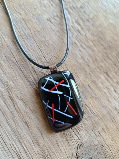 Fused glass pendant on black cord necklace with abstract white, blue, red lines; quirky art pendant, handmade jewellery.