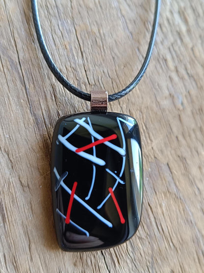 Fused glass pendant on black cord necklace with abstract white, blue, red lines; quirky art pendant, handmade jewellery.