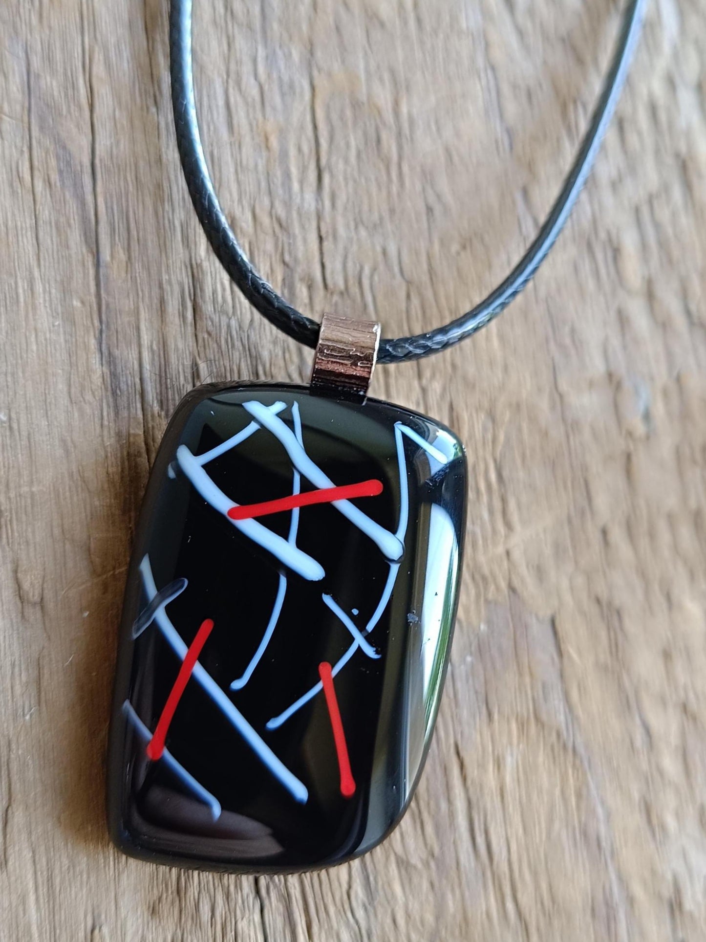 Fused glass pendant on black cord necklace with abstract white, blue, red lines; quirky art pendant, handmade jewellery.