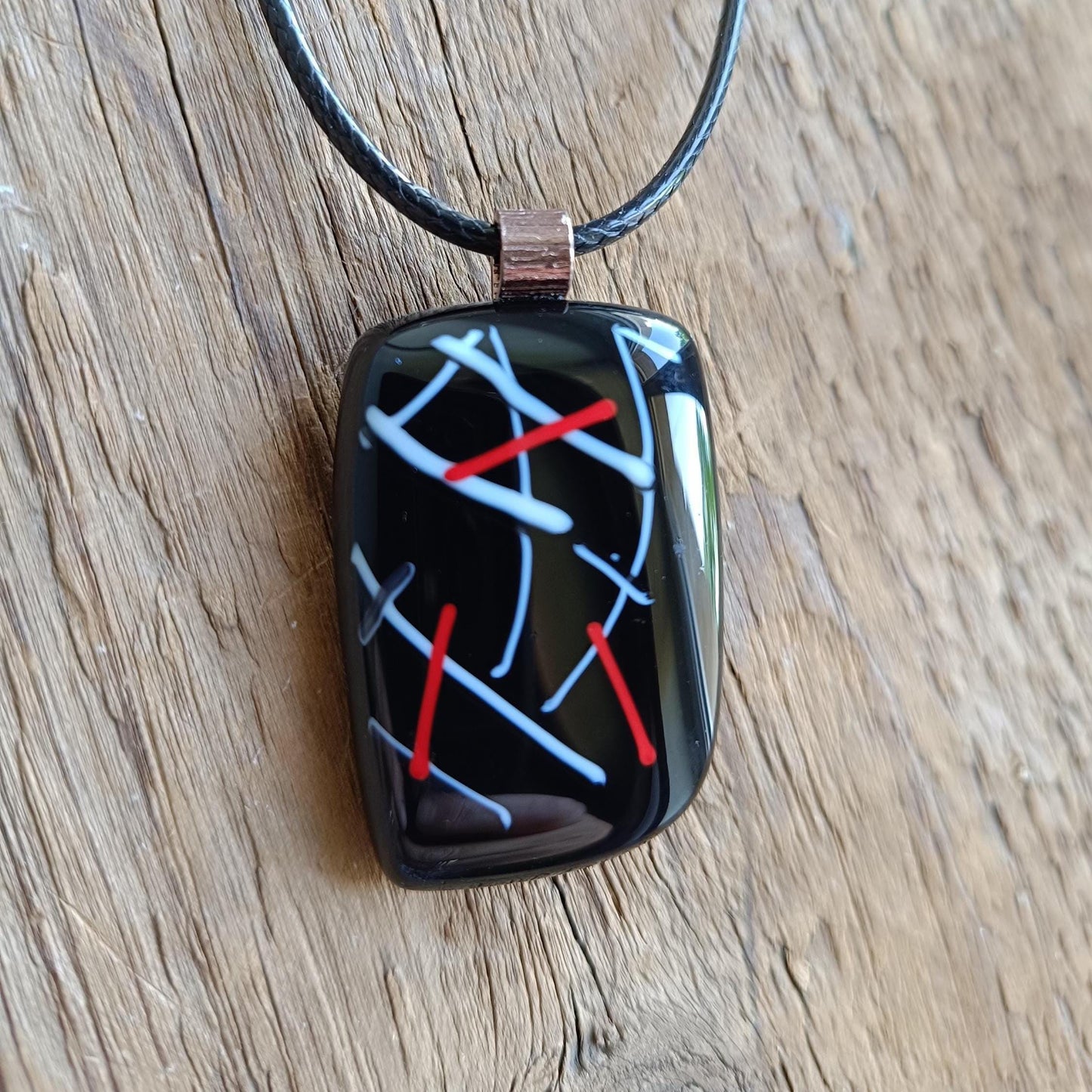 Fused glass pendant on black cord necklace with abstract white, blue, red lines; quirky art pendant, handmade jewellery.